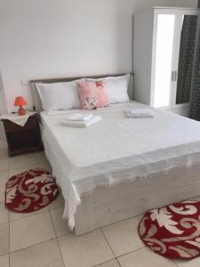 1 dormitorio con 1 cama blanca grande con almohadas rosas en Pensiunea Scoika Steaguri Neptun en Neptun