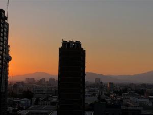 a silhouette of a building in a city at sunset at Metro U de Chile Santiago Centro in Santiago