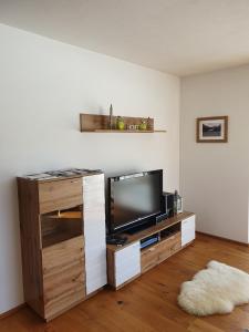 - un salon avec une télévision sur un centre de divertissement en bois dans l'établissement Ferienwohnung App. MOUNTAIN VIEW, à Fieberbrunn