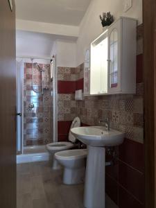 łazienka z 2 toaletami, umywalką i prysznicem w obiekcie Borgo Bellavista Isola Rossa w mieście Isola Rossa