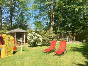 two red chairs sitting in the grass in a yard at Haus Nicole in Cuxhaven