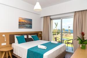 una camera da letto con un letto e vista sull'oceano di Helios Bay Hotel and Suites a Paphos Altre 37 foto