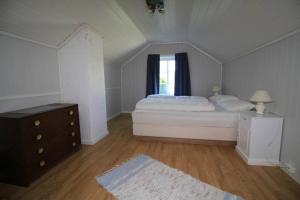 a white bedroom with a bed and a window at Bellahuset in Sæbø