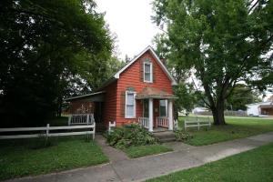 a small red house with a white fence in a yard at Downtown 2 Bedroom Cottage, Sleeps 6, Walking Distance to Honeywell, Downtown Restaurants, Shopping in Wabash