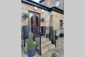 a brick house with a black fence and stairs at Beautiful self contained apartment with garden in Glasgow