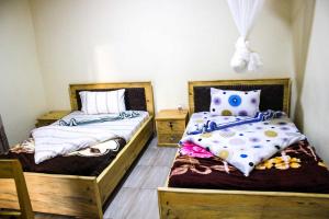 dos camas sentadas una al lado de la otra en una habitación en Akagera Neighbors, en Kabarondo