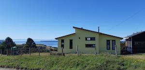 ein Haus auf einem Hügel mit dem Ozean im Hintergrund in der Unterkunft Cabaña Quiquel, Dalcahue, Chiloe in Dalcahue