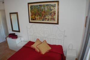 Un dormitorio con una cama roja con una pintura en la pared en Le casette di Frà al Bondì, en Santa Severa