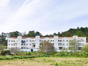 a large white building with a hill in the background at Apartmento SOMA Aljezur in Aljezur
