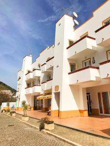 a large white building with balconies on a street at Homestay Attic Private Bedroom in Aljezur