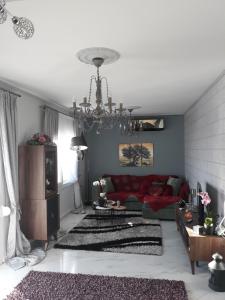 een woonkamer met een rode bank en een kroonluchter bij Caldera Premium Villa in Kavala