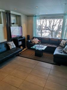 uma sala de estar com um sofá de couro e uma televisão em Malvik em Malvik