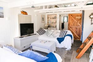 a living room with a white couch and a tv at ROES IN VREDE - RUST IN PEACE in Witsand