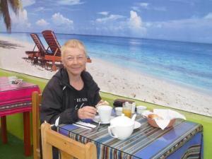 une femme assise à une table en face de la plage dans l'établissement Hostel Fuentes, à Arequipa