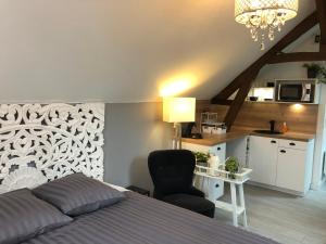 a bedroom with a bed and a chair and a kitchen at Maison Quatre Freres in Louviers