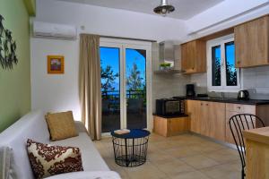 a living room with a white couch and a kitchen at House in Εndless green - Arethousa, Ikaria in Evdilos