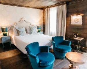 una camera con un letto e due sedie blu di Hotel Le Castel a Chamonix-Mont-Blanc