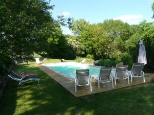a group of chairs and an umbrella next to a pool at gites Les Lebes - Grange loft in Sempesserre