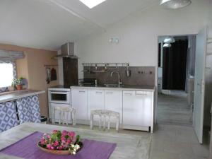 a kitchen with white cabinets and a table with flowers at gites Les Lebes - Grange loft in Sempesserre