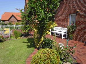 a white bench sitting next to a brick building at Lachmöwe in Dornumersiel