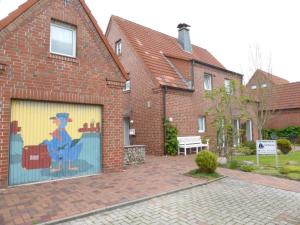 a building with a mural of a man on a garage door at Lachmöwe in Dornumersiel