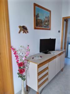 a desk with a computer and flowers in a room at Come a casa - near VENEZIA in Oriago Di Mira