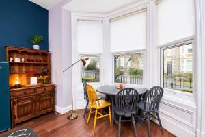 a dining room with a table and chairs and windows at Lovely Abode in Newcastle - Sleeps 4 in Newcastle upon Tyne