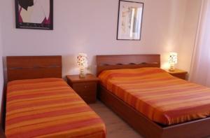 2 Betten in einem Schlafzimmer mit 2 Lampen an Nachttischen in der Unterkunft Orange Home in Marina di Castagneto Carducci