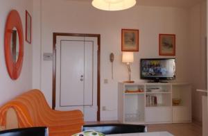 ein Wohnzimmer mit einem TV, einem Sofa und einem TV in der Unterkunft Orange Home in Marina di Castagneto Carducci