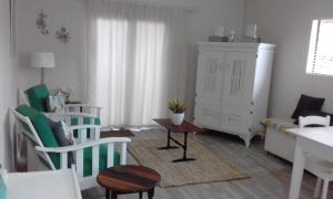 a living room with white chairs and a table at Marlin Cottage in Chintsa +9 photos