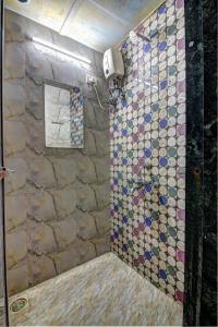 a bathroom with a shower with a tiled wall at Sunshine Backpackers, Airport in Mumbai