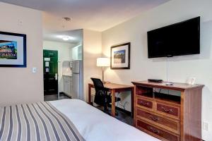 a hotel room with a bed and a desk with a television at Suburban Studios Westminster Denver North in Westminster