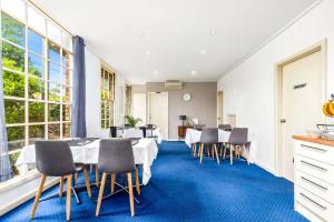 Comfort Inn Greensborough في ملبورن: غرفة طعام مع طاولات بيضاء وكراسي ونوافذ