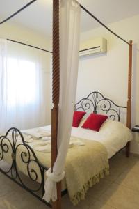a bedroom with a four poster bed with red pillows at Melania Gardens in Paphos