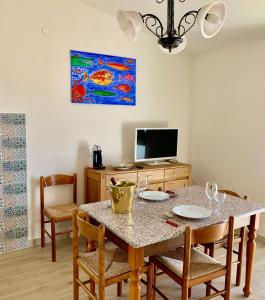 jadalnia ze stołem z krzesłami i telewizorem w obiekcie Borgo Bellavista Isola Rossa w mieście Isola Rossa