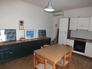 a kitchen with a table and a white refrigerator at Casale Al Mare in Marina di Campo
