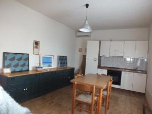 a kitchen with white cabinets and a table and chairs at Casale Al Mare in Marina di Campo