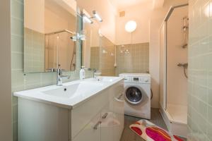 een badkamer met een wastafel en een wasmachine bij Appartement vue mer in Bénodet