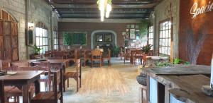 un restaurante con mesas y sillas de madera y ventanas en Spacio Caliraya Bed & Breakfast, en Lumban