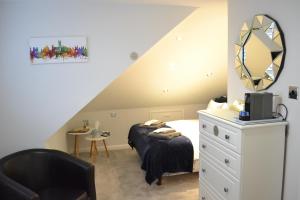 1 dormitorio con cama, espejo y silla en Harriet House B&B en Canterbury