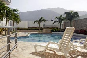 two white chairs sitting next to a swimming pool at Apartamento de Yuly in Santa Marta