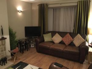 a living room with a brown couch and a television at Rondo, Ballymena, Nr Ireland in Ballymena