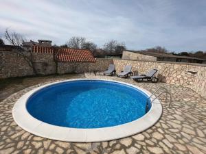 a swimming pool with two chairs and a stone wall at Attractive Holiday Home with Pool bubble bath Patio Courtyard in Barbariga