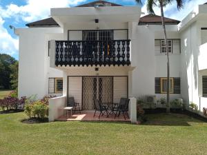 a white house with chairs and a balcony at 213 Golden Grove, Rockley in Bridgetown