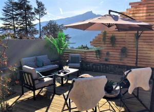 un patio con mesa, sillas y sombrilla en Loft Christina moderne et confortable, vue lac, climatisation, parking, en Aix-les-Bains