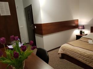 ein Hotelzimmer mit einem Bett und einer Vase aus Blumen auf dem Tisch in der Unterkunft Pokoje Bakos Radocza in Radocza