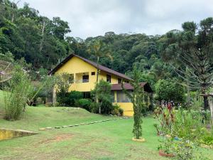 a yellow house in the middle of a yard at Pousada Recanto da Mata in Marechal Floriano
