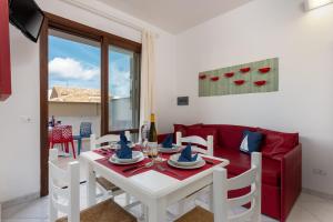 a living room with a white table and a red couch at Le Palme Di Conturrana in San Vito lo Capo