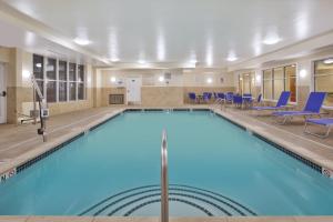 duży basen w pokoju hotelowym z niebieskimi krzesłami w obiekcie Holiday Inn Express Hotel & Suites Auburn Hills, an IHG Hotel w mieście Auburn Hills