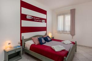 a bedroom with a bed with a red and white headboard at Le Palme Di Conturrana in San Vito lo Capo